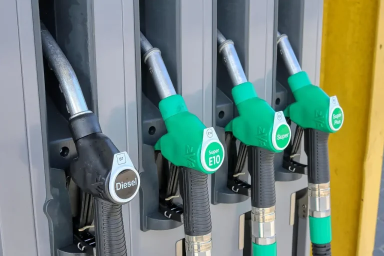 Quatre pistolets de station-service alignés, le diesel noir à gauche et les essences E10 et Super en vert