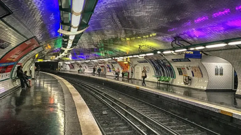 Quai courbe de la station Arts et Métiers, voûte carrelée aux reflets colorés, voyageurs sur le quai d'en face