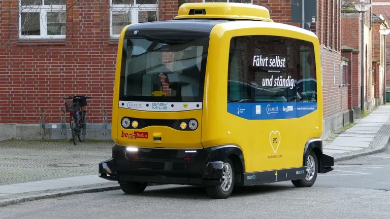 Navette autonome jaune EasyMile de la BVG garée dans une rue pavée devant un bâtiment en briques rouges à Berlin