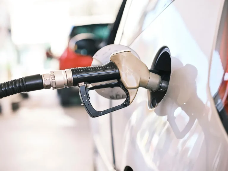 Pistolet de carburant noir engagé dans le réservoir ouvert de la voiture blanche