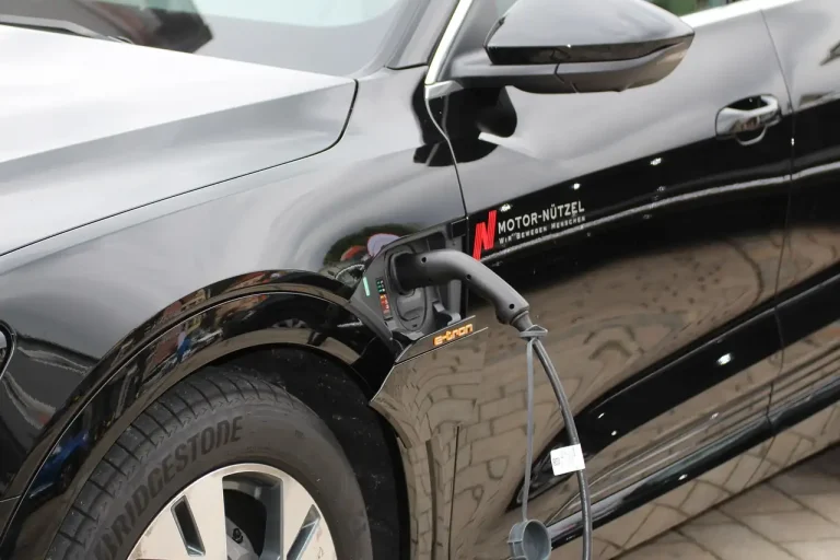 Voiture électrique noire branchée à un câble de recharge sur son aile avant gauche