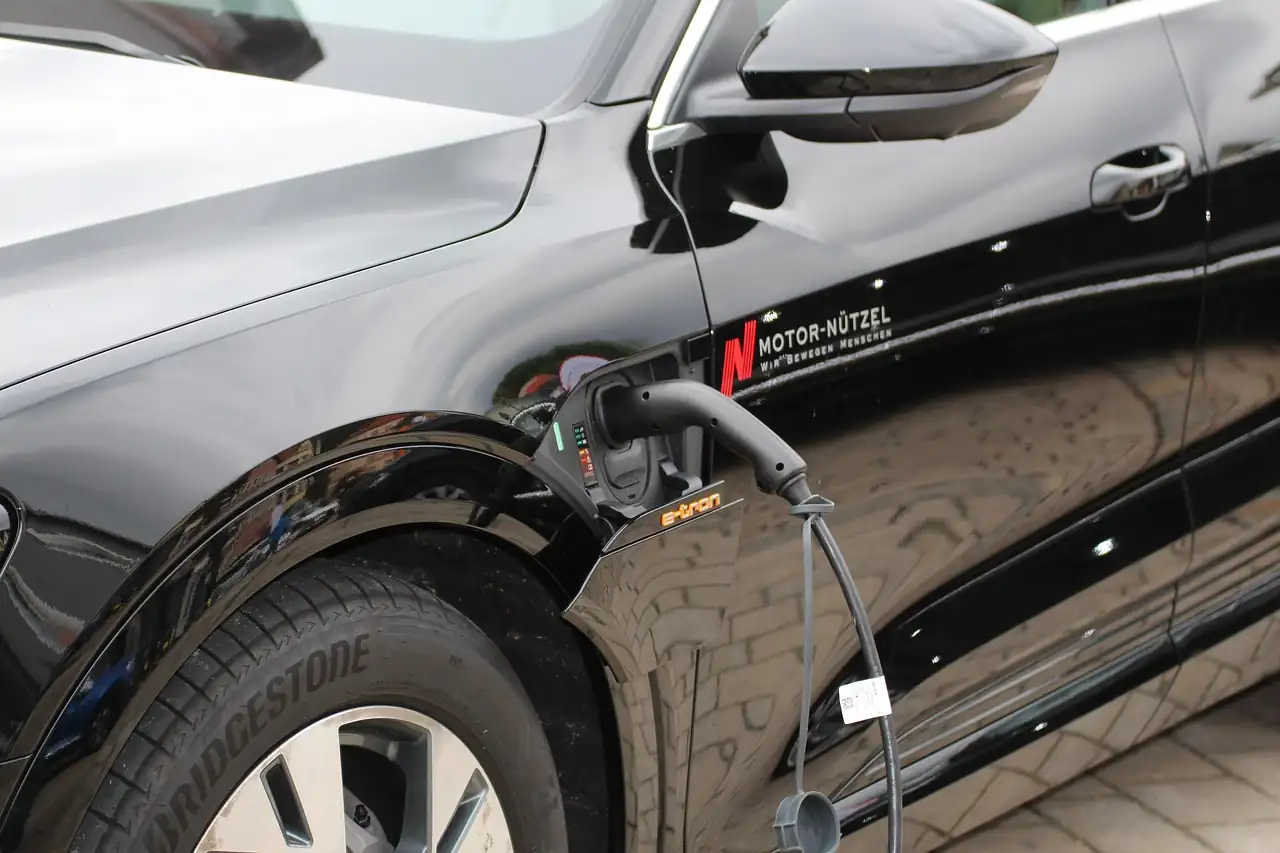 Voiture électrique noire branchée à un câble de recharge sur son aile avant gauche
