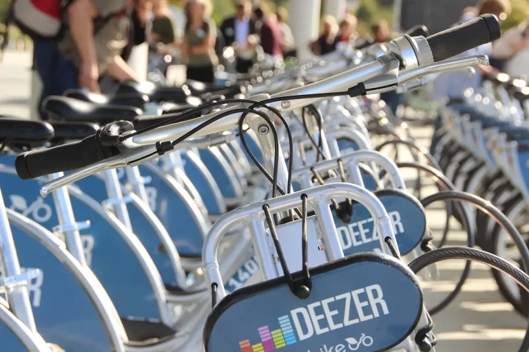 Rangée de vélos de location gris et bleus alignés en station, guidons au premier plan