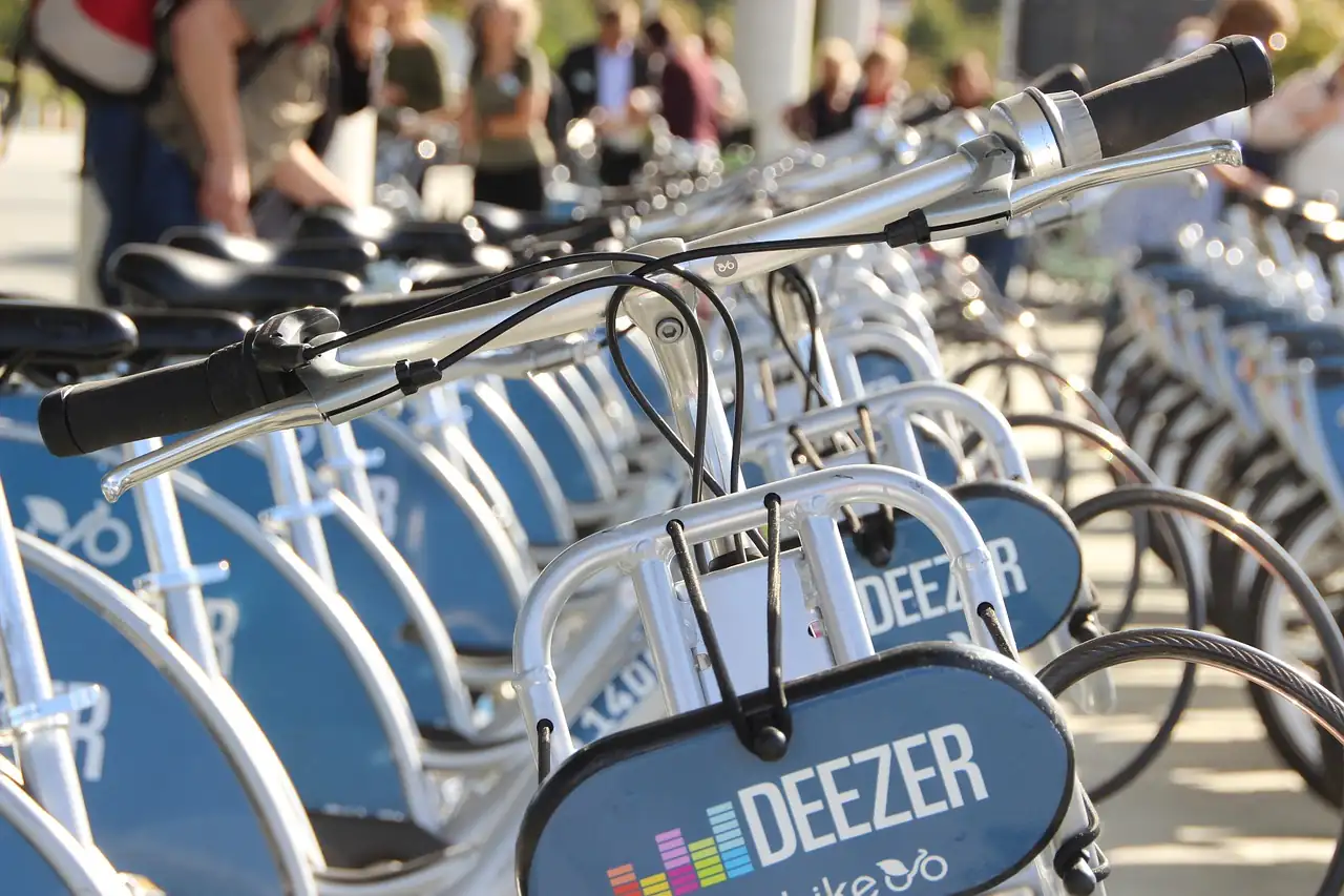 Rangée de vélos de location gris et bleus alignés en station, guidons au premier plan