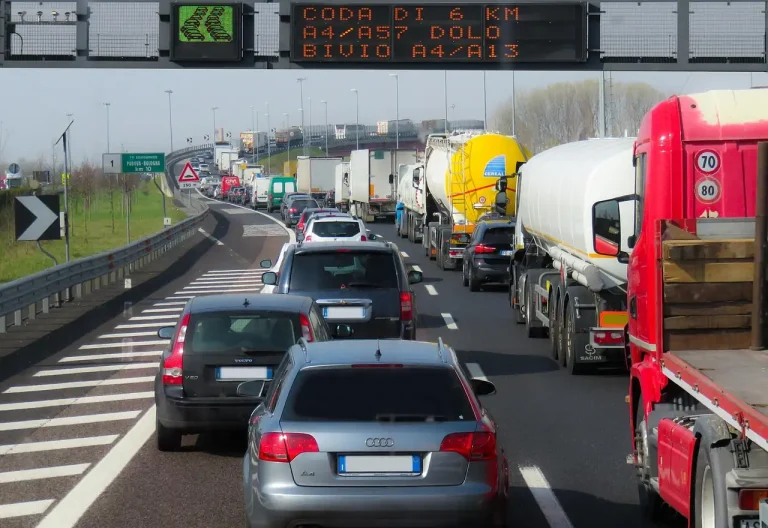 Longue file de voitures et de poids lourds immobilisés sur une autoroute sous un panneau annonçant un bouchon de 6 km