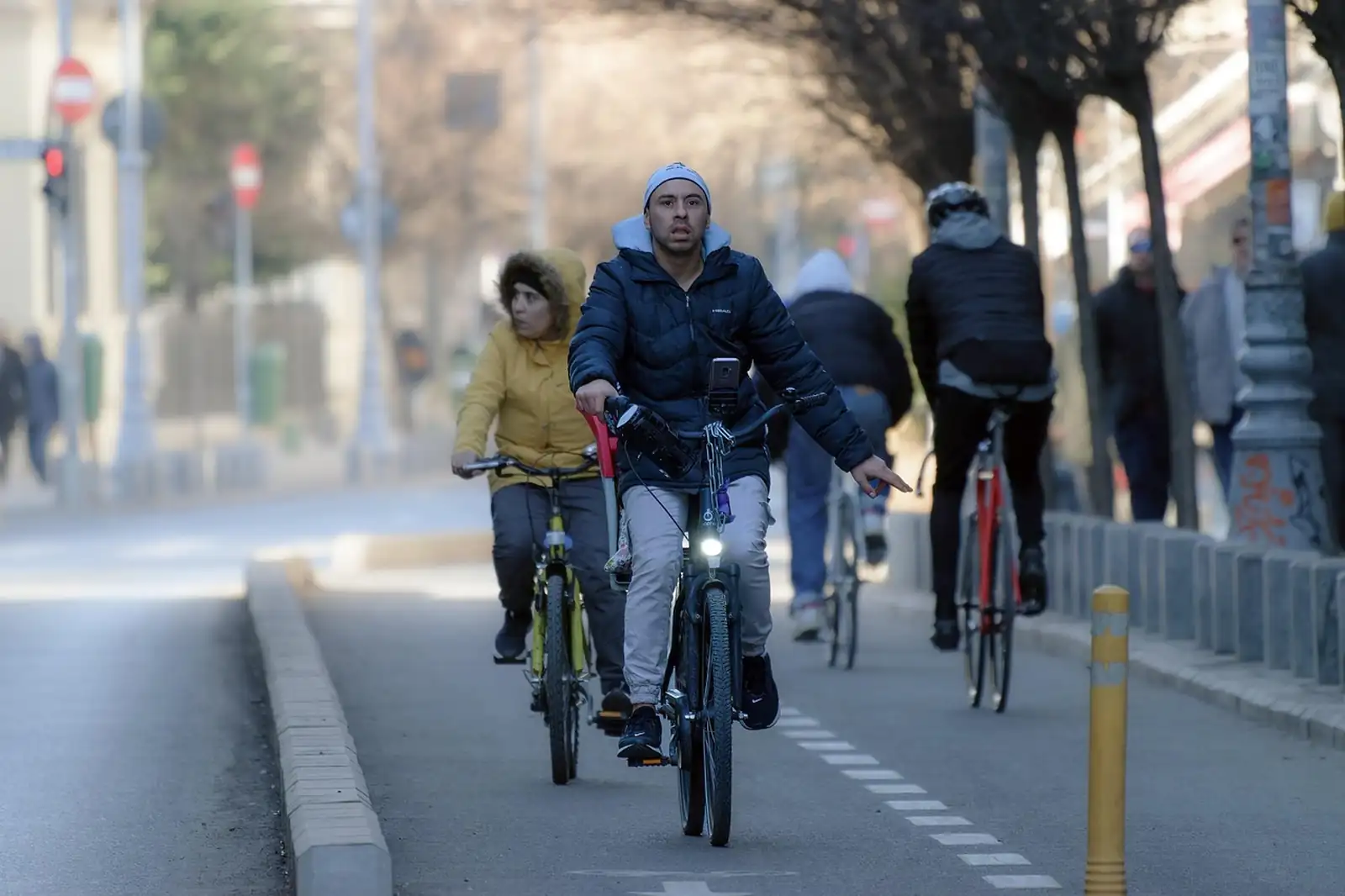 Cyclistes en manteau d'hiver sur une piste cyclable séparée de la circulation