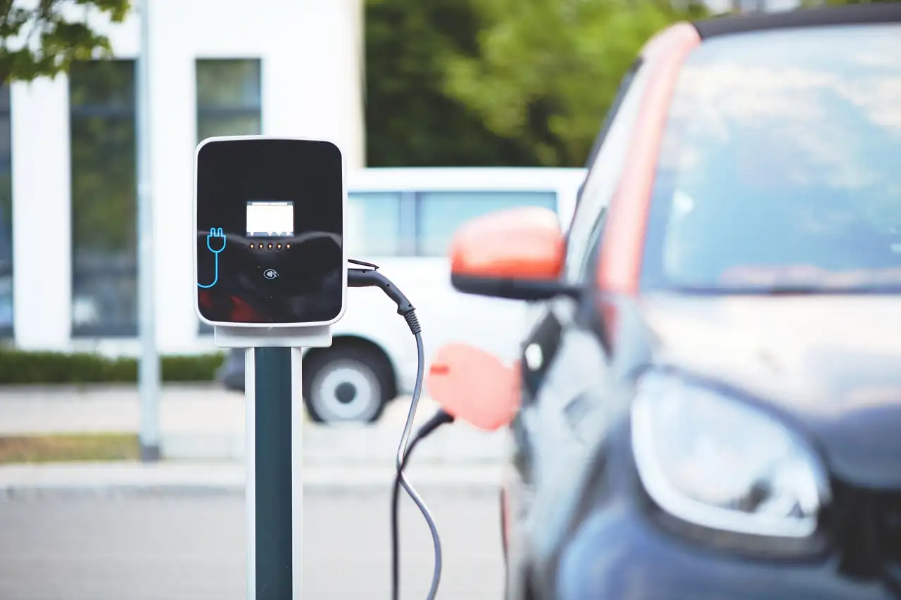 Borne de recharge avec son câble branché, une petite voiture garée juste derrière