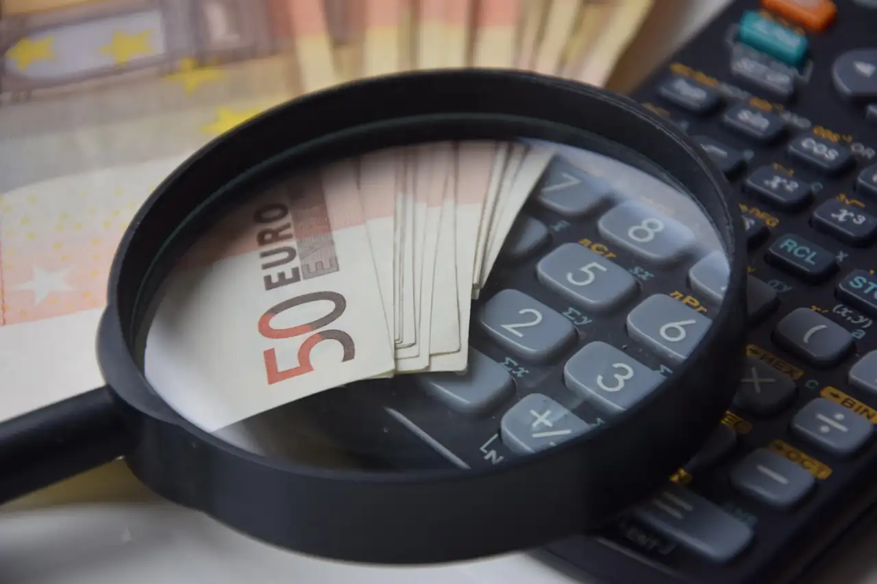Loupe posée sur des billets de cinquante euros et sur le clavier de la calculatrice