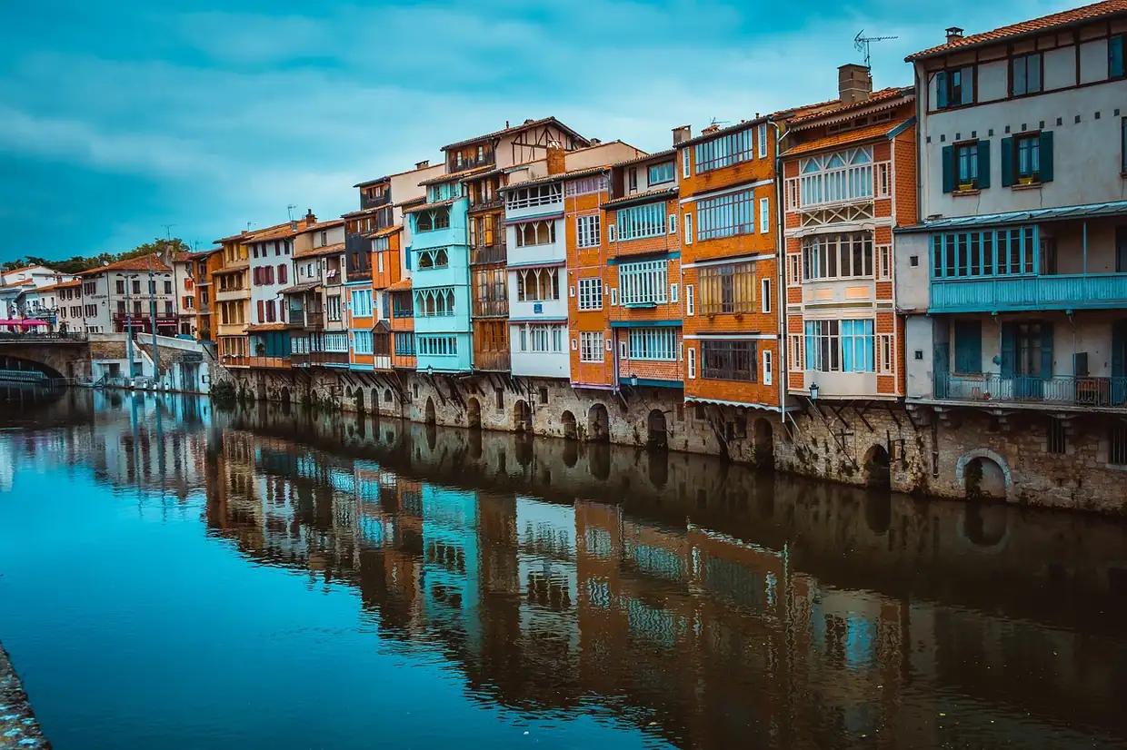 Maisons colorées sur pilotis de pierre le long de la rivière Agout à Castres, reflets dans la rivière calme