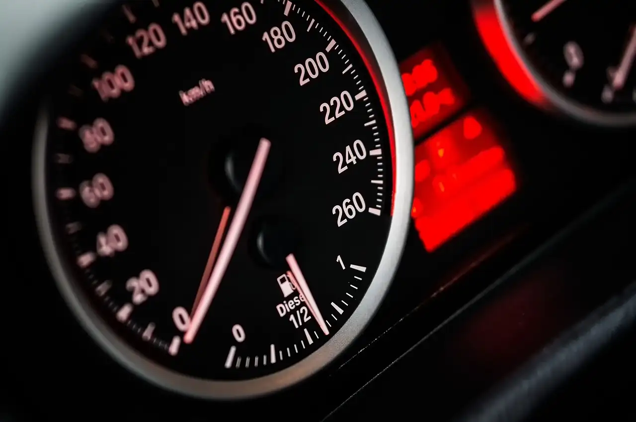 Compteur de vitesse noir éclairé en rouge, avec la jauge de gazole à moitié pleine