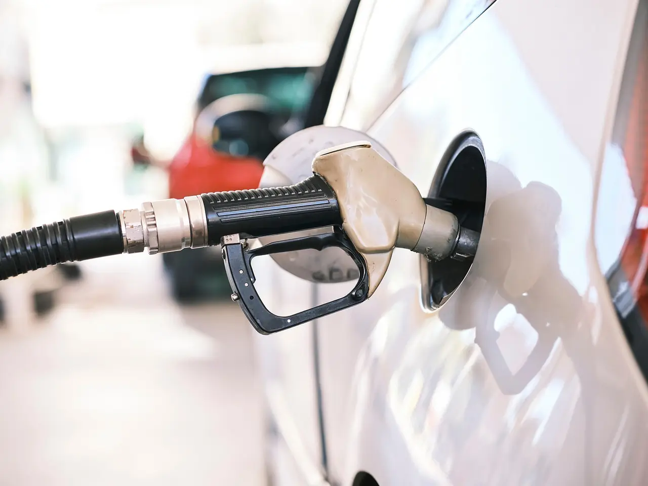 Pistolet de carburant noir engagé dans le réservoir ouvert de la voiture blanche