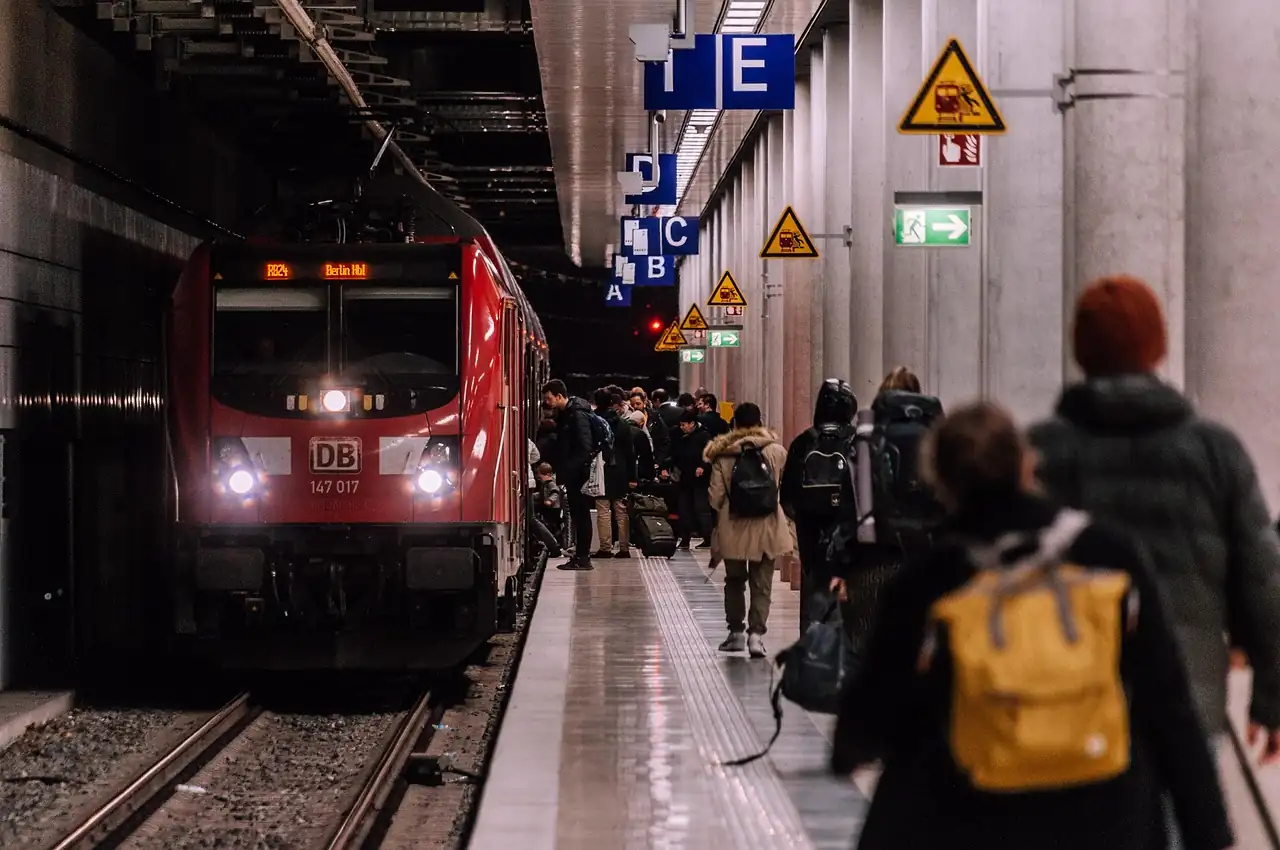 Voyageurs en manteau avec sacs à dos marchant sur un quai souterrain le long du train régional rouge