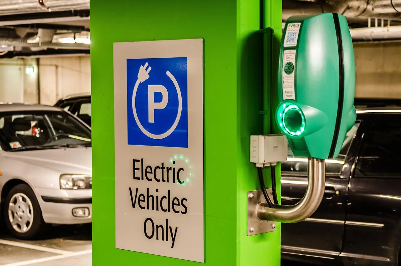 Borne murale verte au voyant allumé dans un parking souterrain réservé aux véhicules électriques
