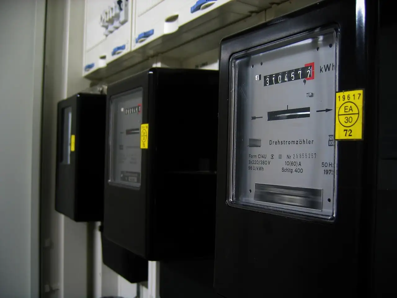 Rangée de vieux compteurs électriques noirs affichant la consommation en kilowattheures