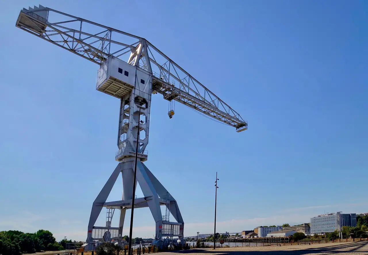 Grande grue portuaire grise sur un quai au bord de la Loire à Nantes, sous un ciel bleu