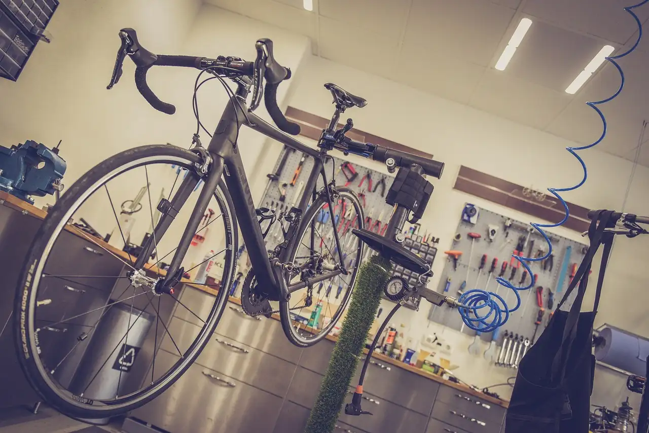 Vélo de route posé sur un pied de réparation dans un atelier, outils accrochés au mur