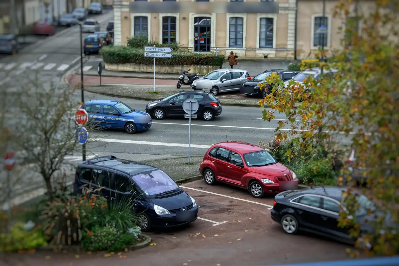 Place de petite ville française en automne, voitures garées et voiture de gendarmerie au carrefour