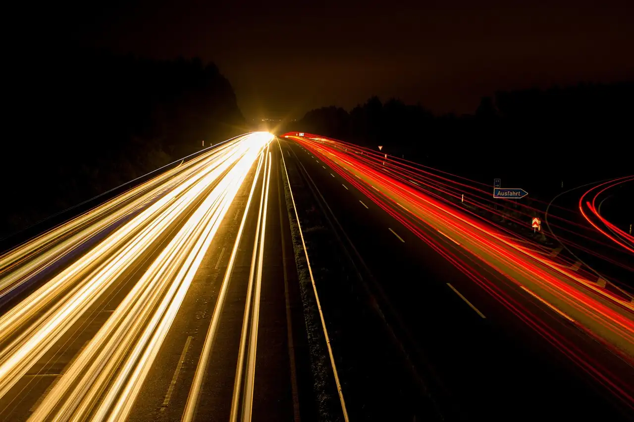 Autoroute de nuit en pose longue, traînées blanches des phares et rouges des feux arrière
