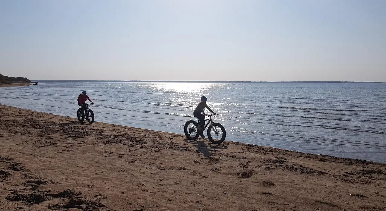 Deux cyclistes sur des vélos à pneus très larges roulant sur une plage de sable au bord de la mer
