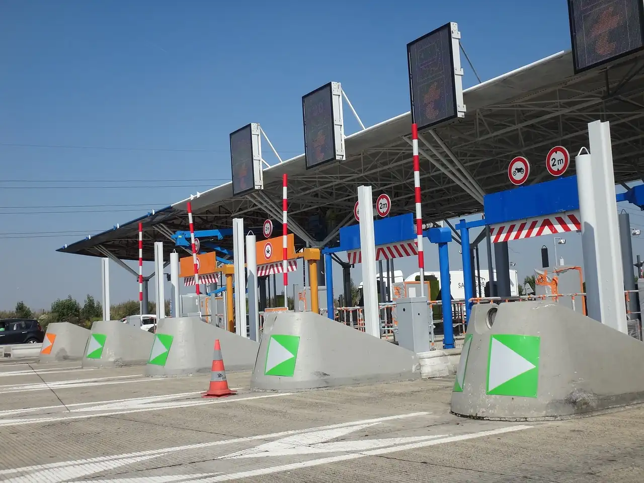 Gare de péage autoroutière vide avec ses voies balisées de flèches vertes et ses panneaux lumineux