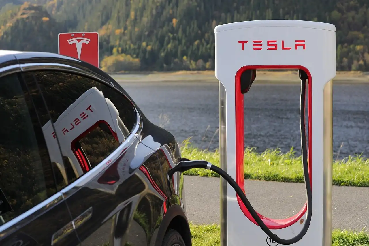 Voiture électrique noire branchée sur une borne de recharge rapide Tesla au bord du lac