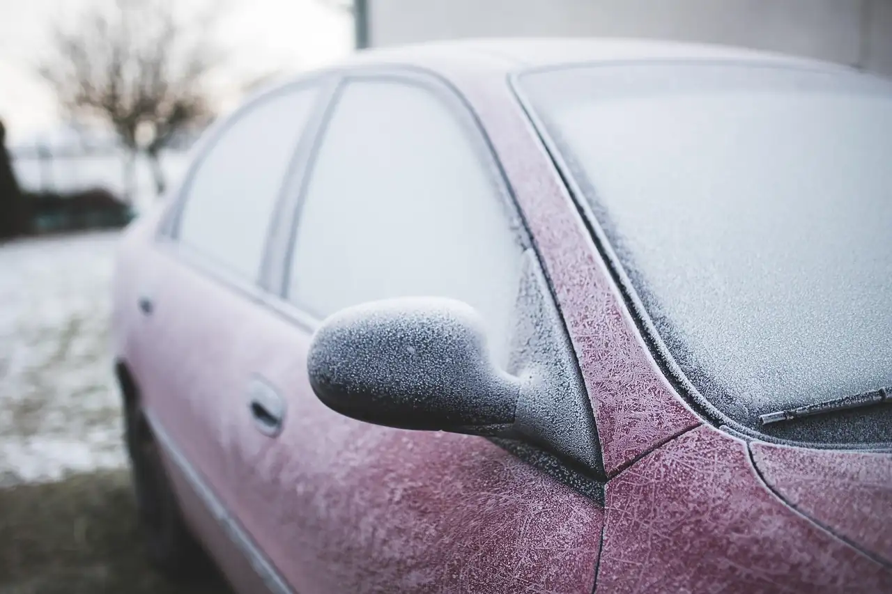 Voiture rouge couverte de givre sur le rétroviseur, la portière et le pare-brise